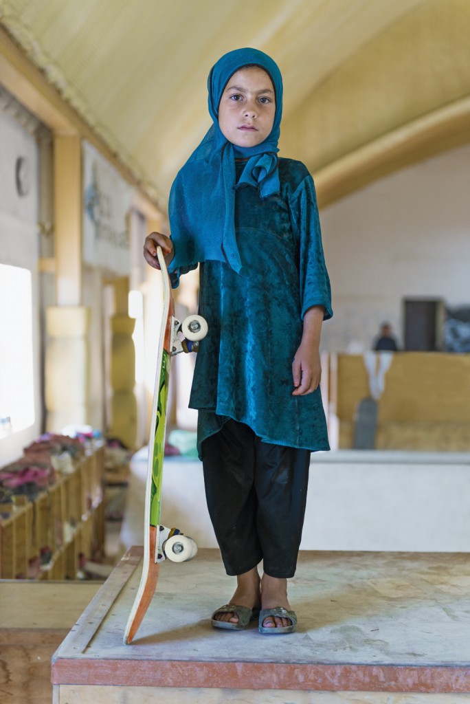 A young girl balances on a skateboard in urban Afghanistan