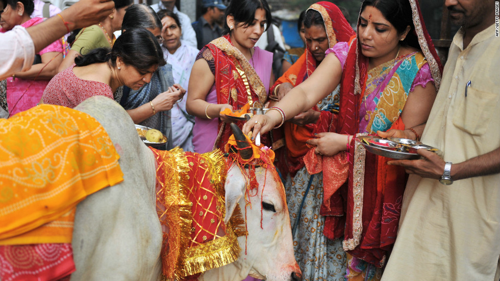 women place beads on a holy cow
