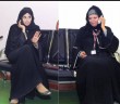 Two Qatari women talk on mobile phones